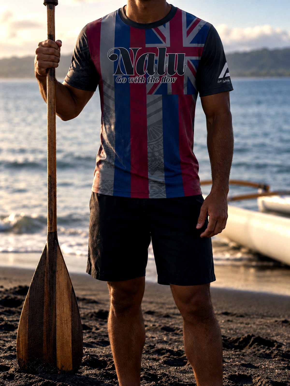 A paddler in the Hae Hawaiʻi Nalu jersey holding a paddle at the water's edge