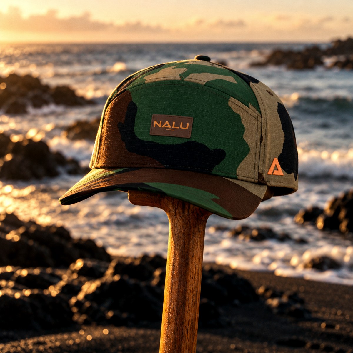 The camo Nalu snapback resting on top of a paddle at the water's edge