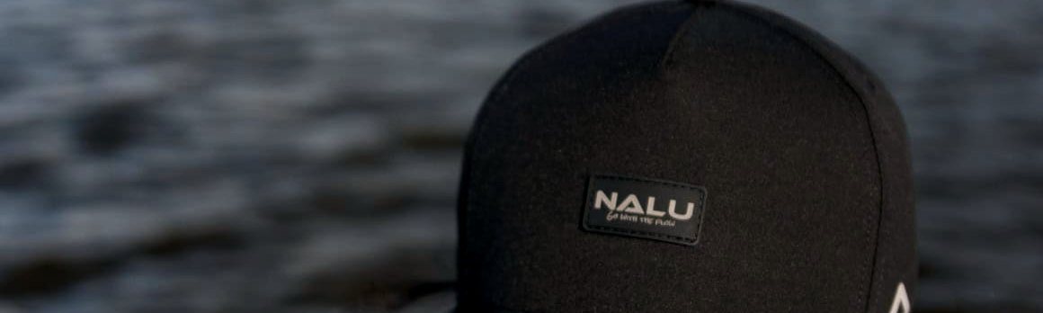 A black Nalu hat with a patch, worn at the water's edge