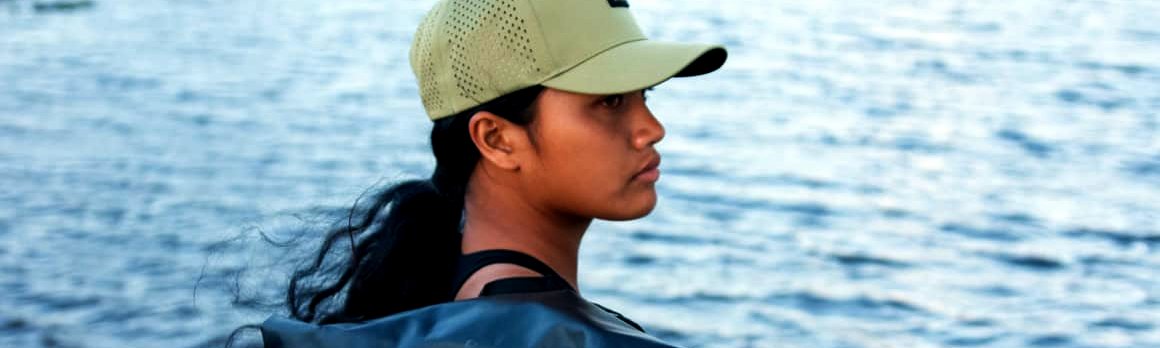 A paddler wears the black Nalu dry bag backpack at the water's edge
