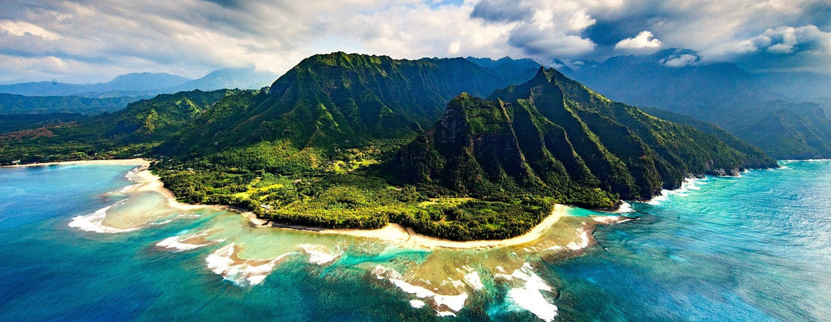 Aerial view of the Nā Pali coast, its green ridges falling to a reef-lined beach